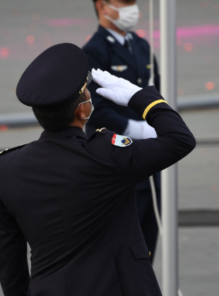 国旗へ敬礼する人物の写真