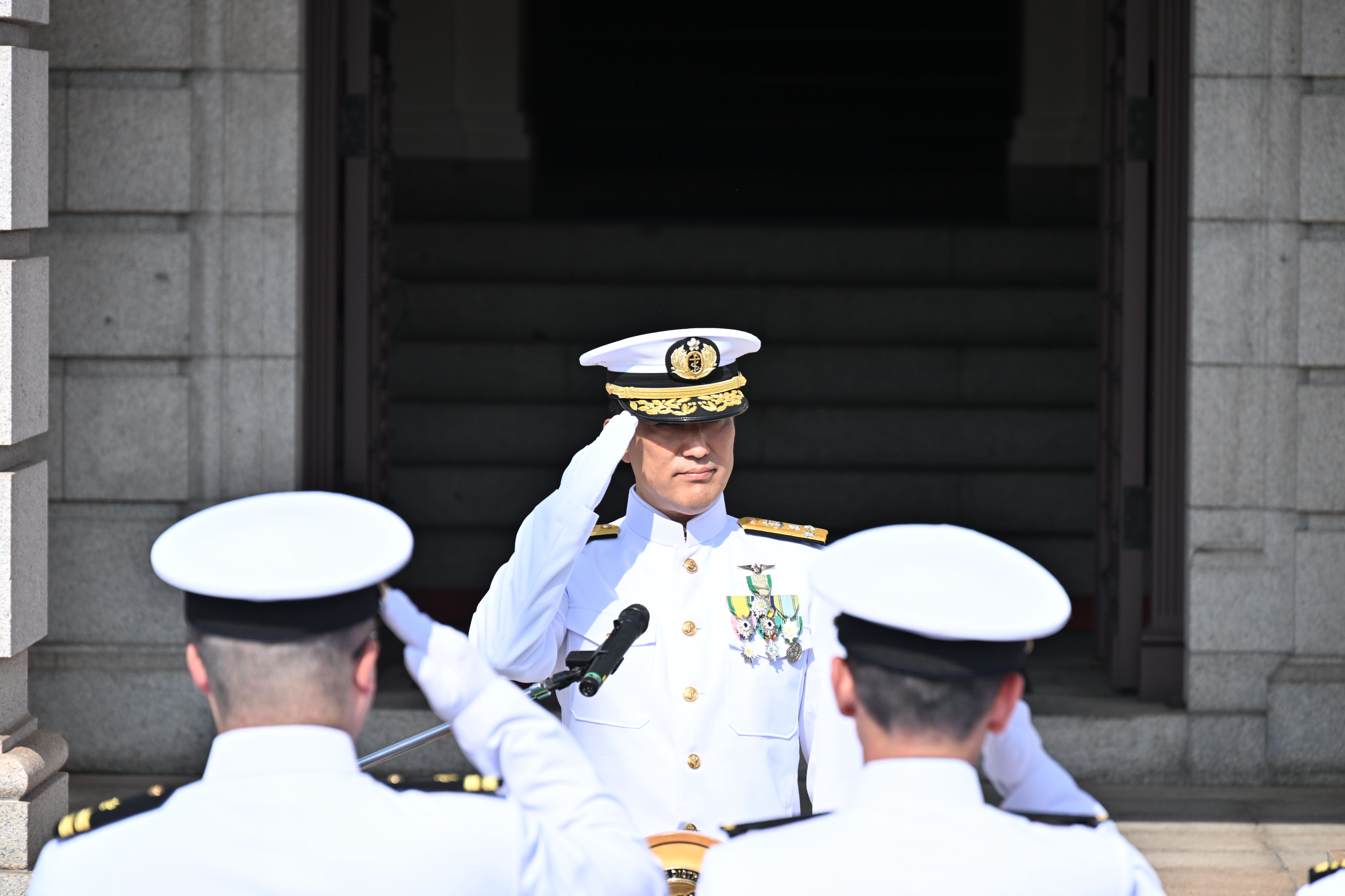 整列した隊員たちに敬礼する松本海将